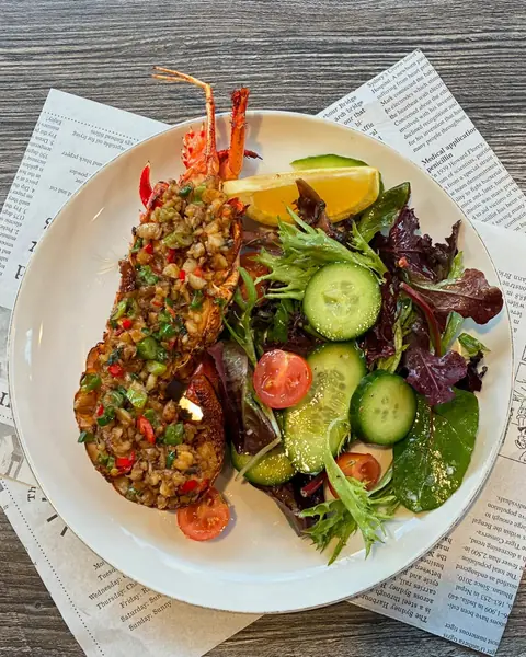 Grilled lobster tail with a side salad on a white plate