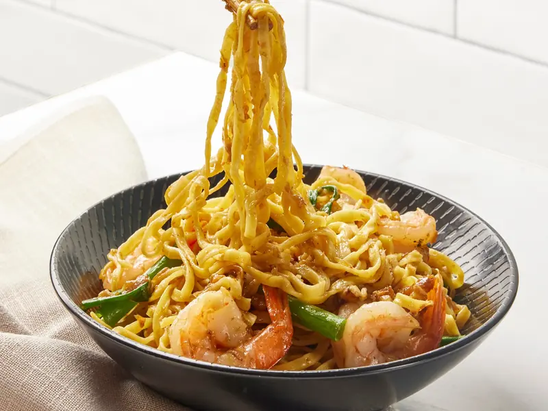 XO egg noodles with prawns lifted from the bowl with chopsticks